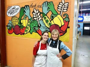 WARF Employee and her mother wearing aprons in front of wall at Second Harvest Foodbank