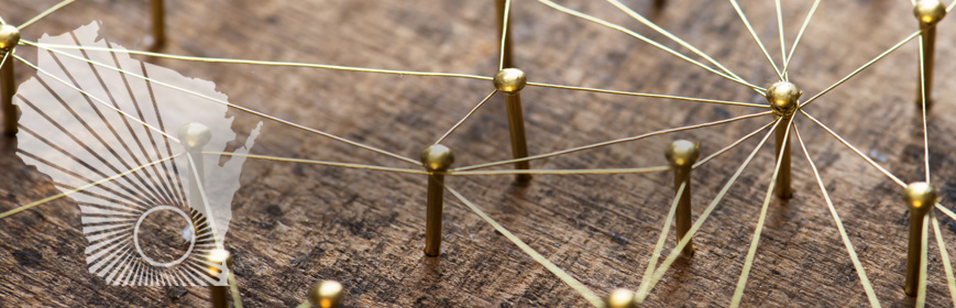 Closeup of small pins nailed to a piece of wood with string attached to, and linking, some of the pins